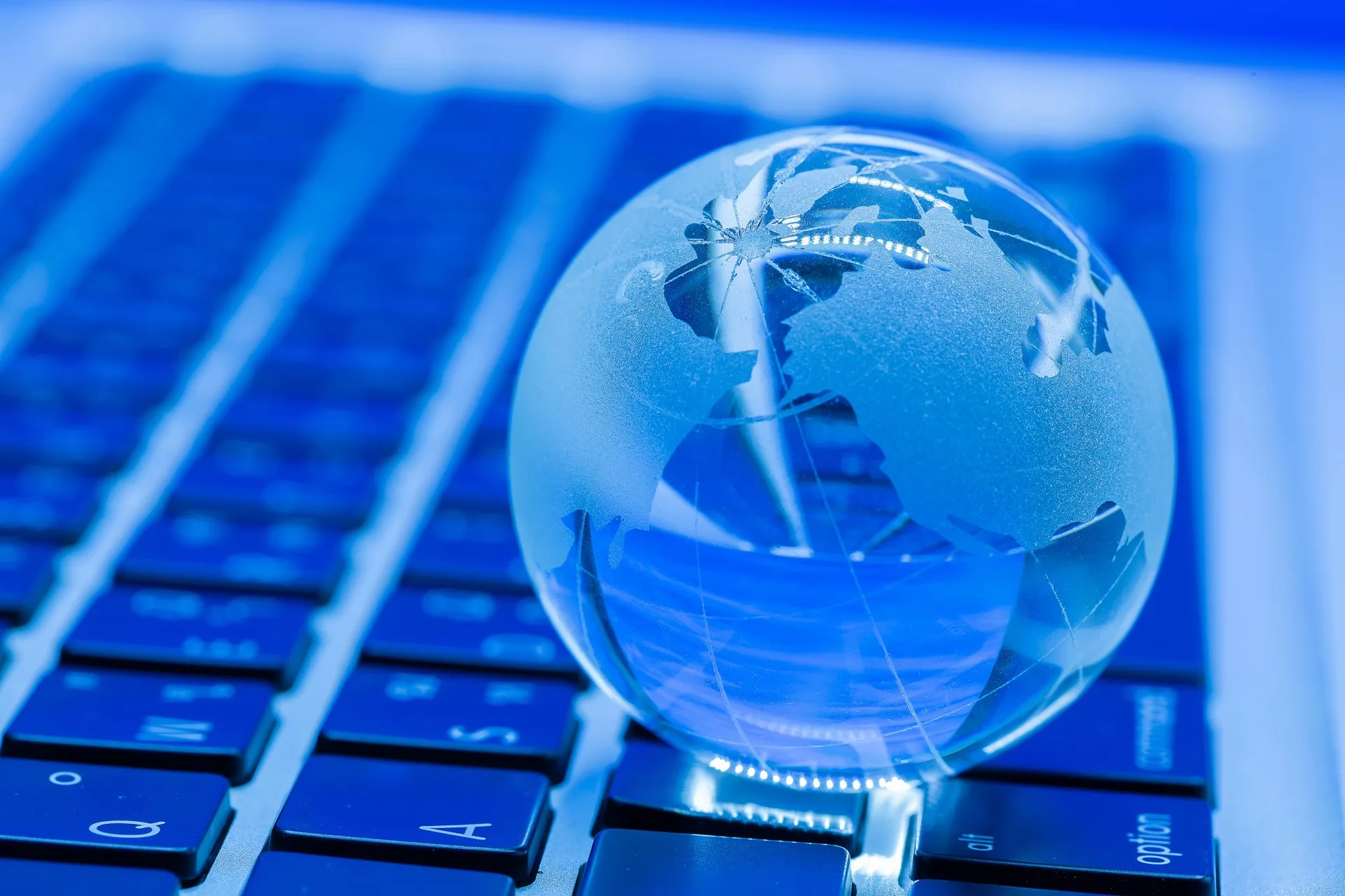 A glass globe resting on a blue computer keyboard