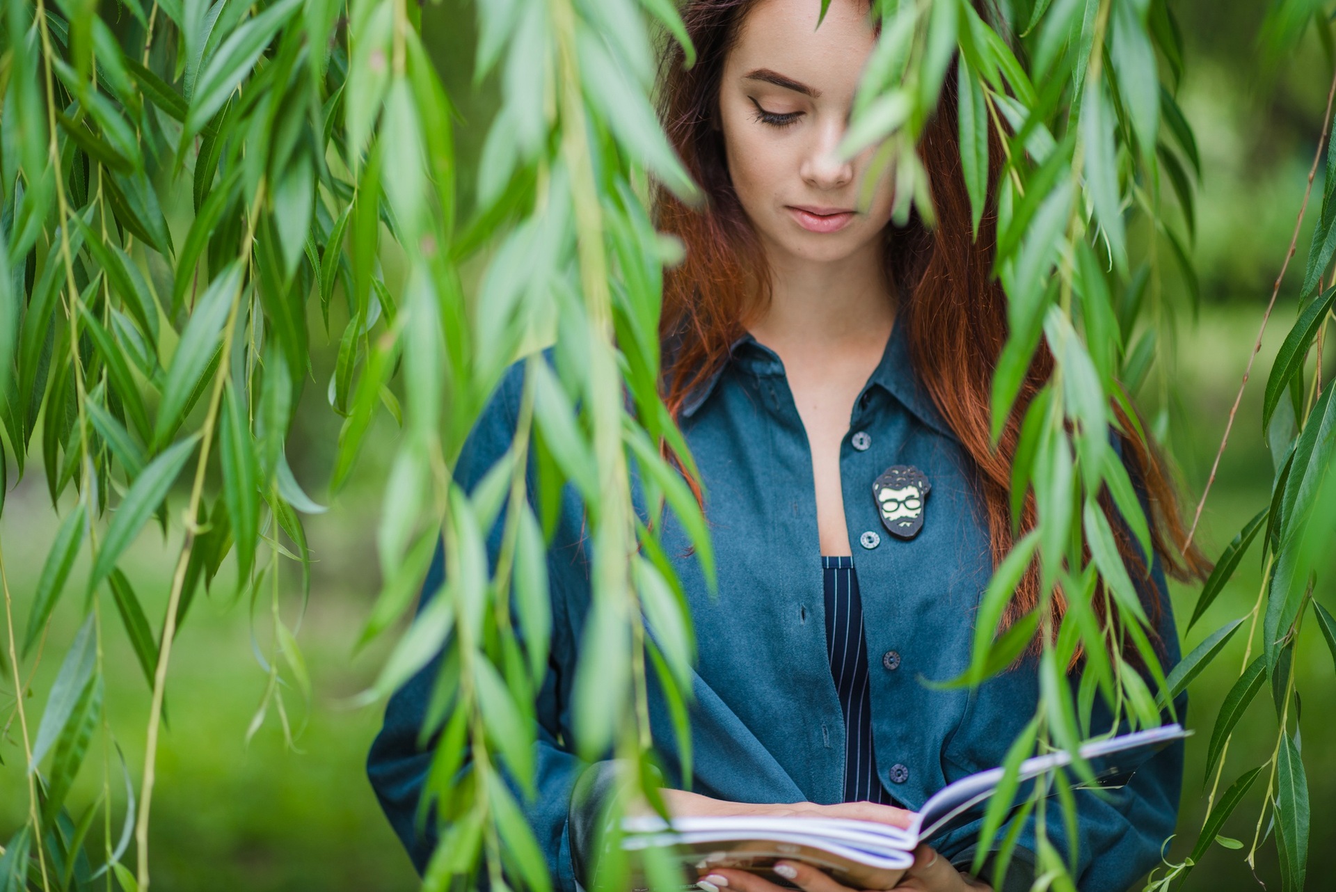 A woman reading among hanging green leaves