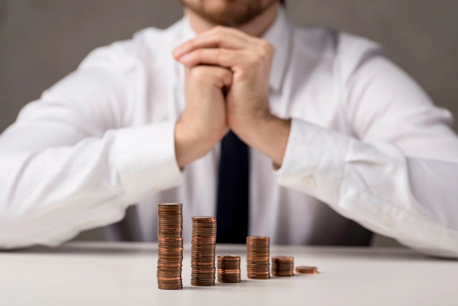 A person seated behind stacks of coins
