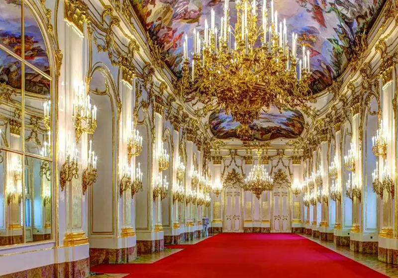 An ornate gilded hall with chandeliers and painted ceilings
