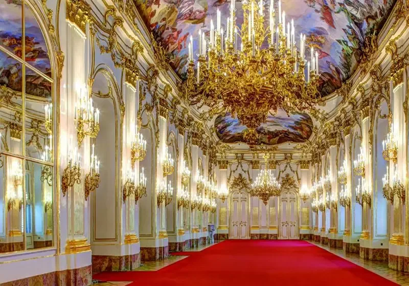 An ornate gilded hall with chandeliers and painted ceilings