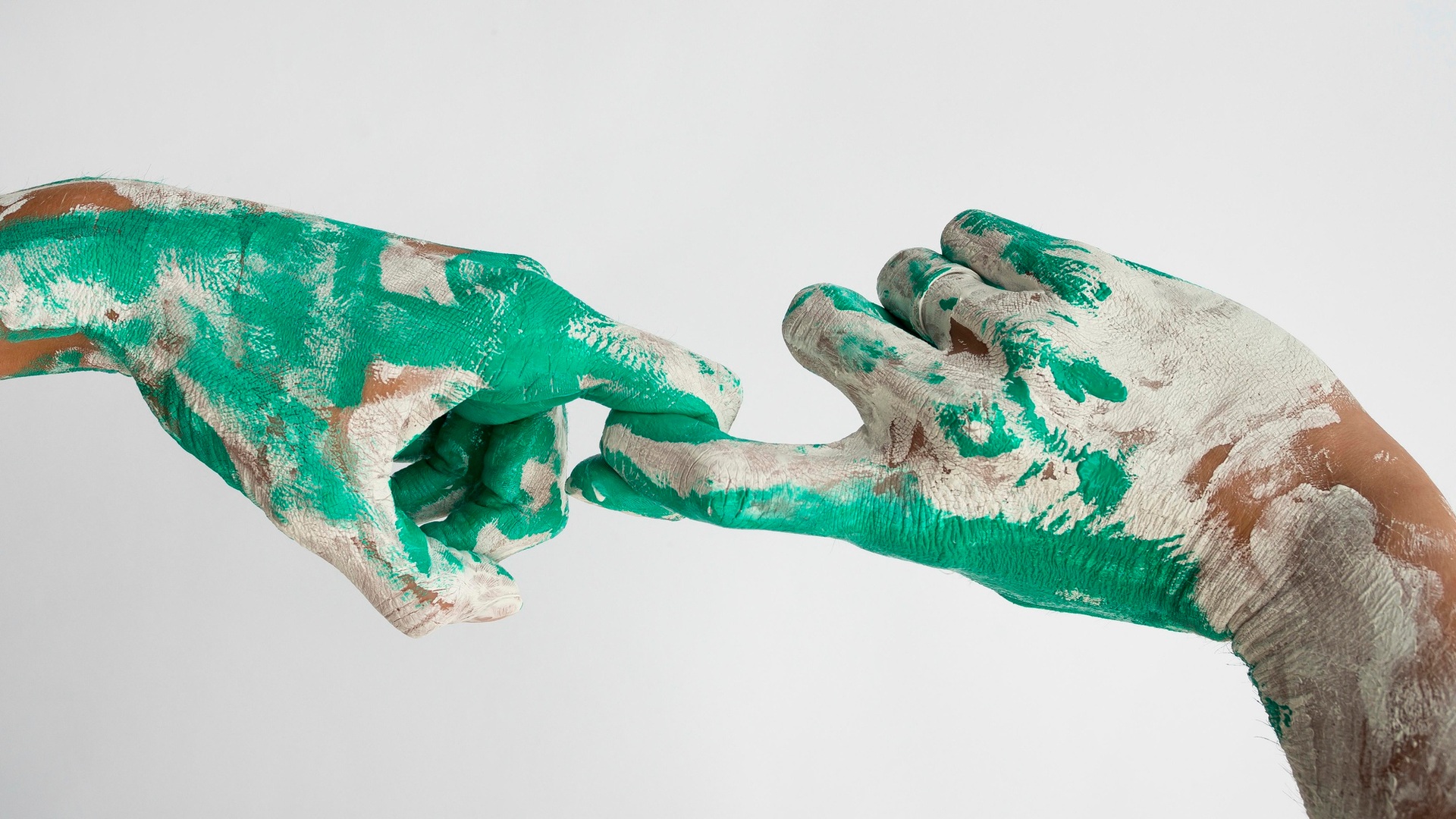 Two paint-covered hands reaching towards each other