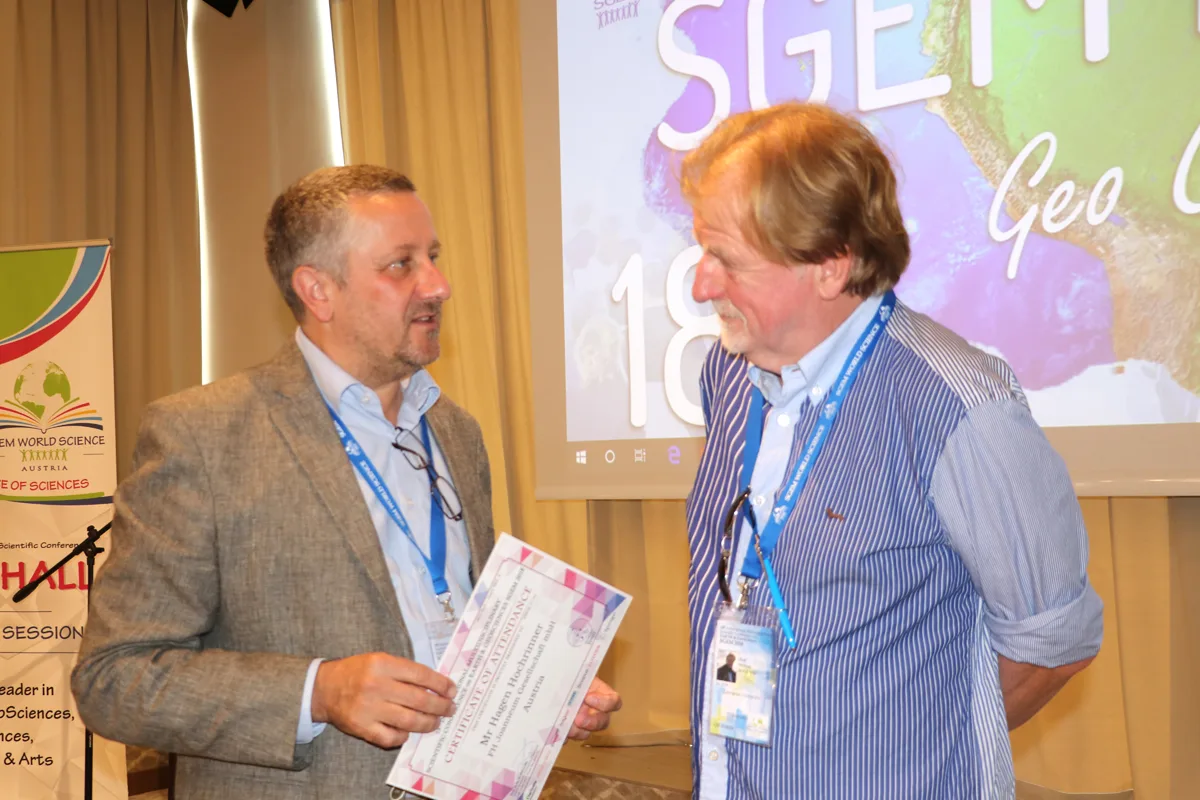 Two SGEM participants talking while holding conference papers