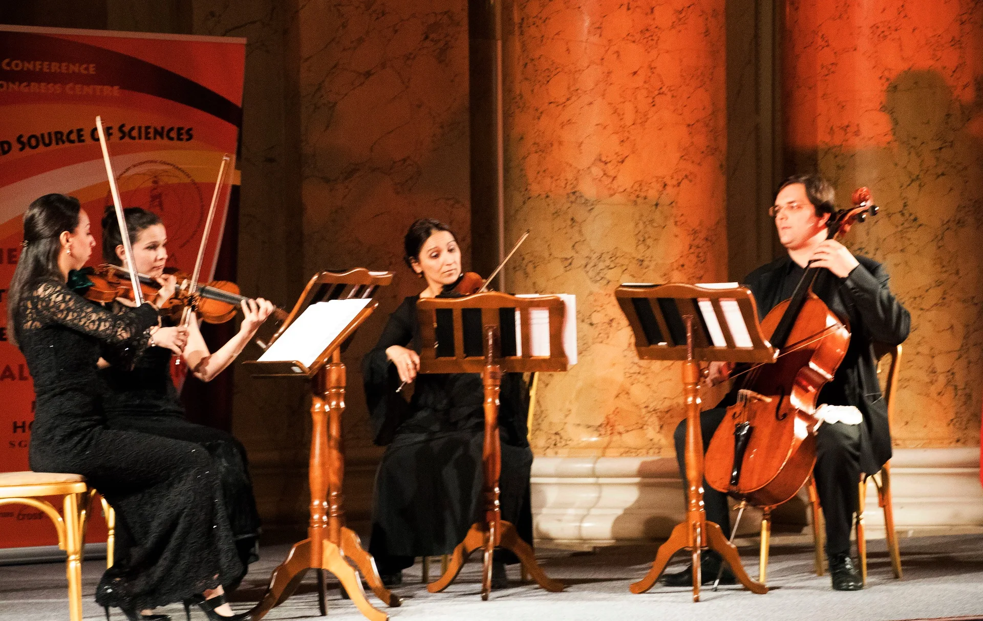 A string ensemble performing between marble columns