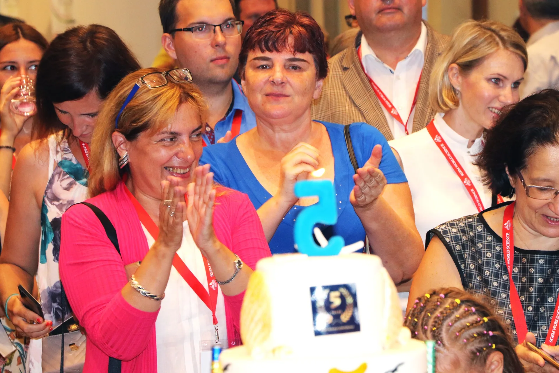 Conference participants applauding beside a celebration cake