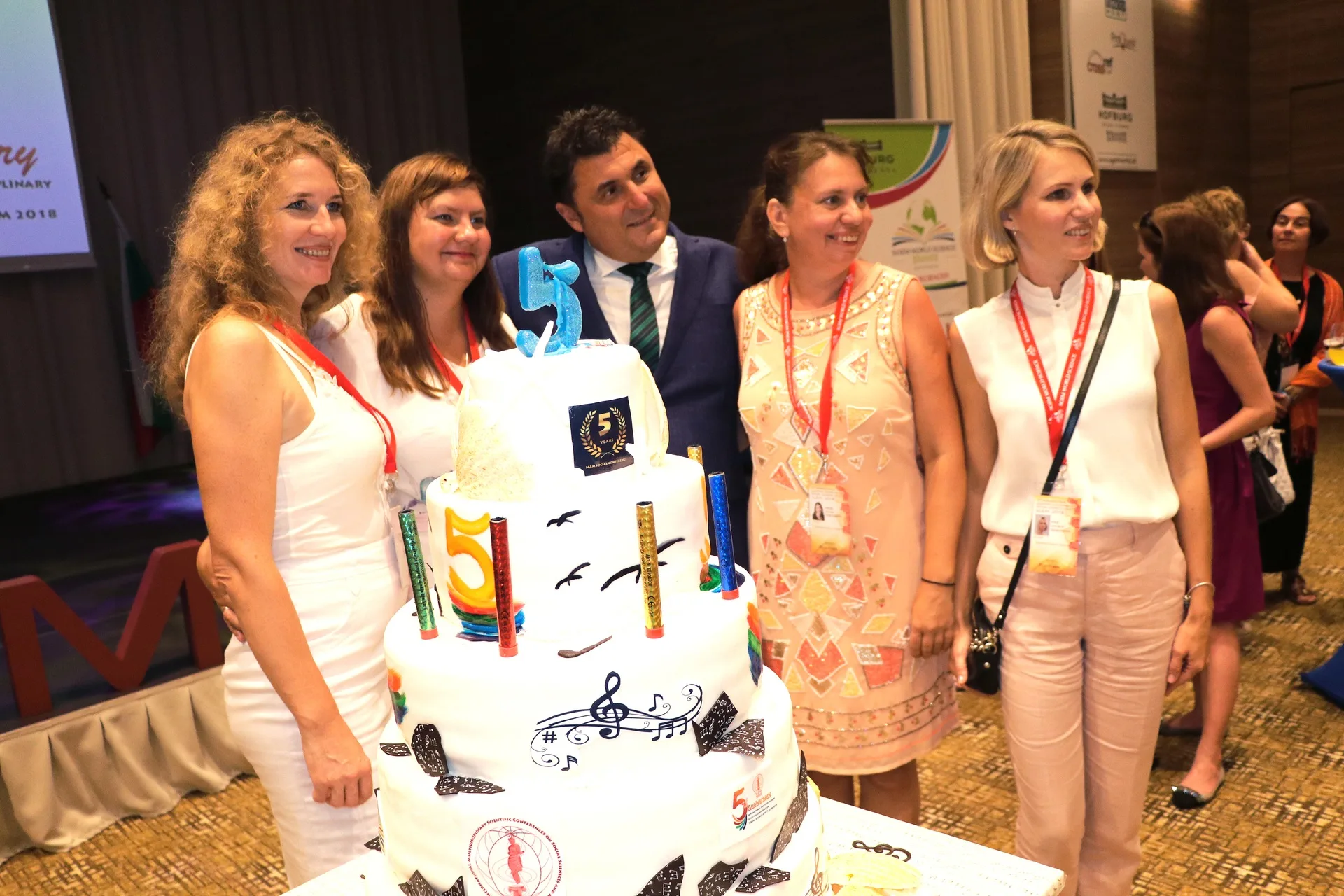 Five participants posing behind a decorated conference cake