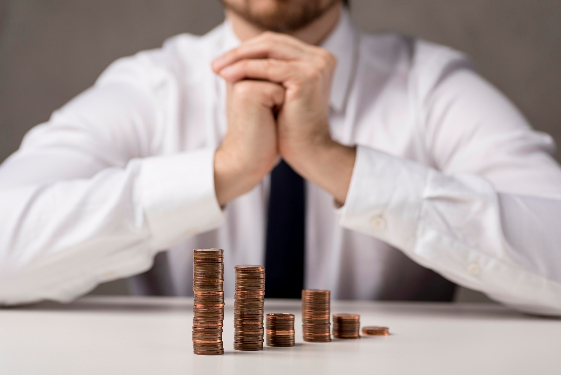 Una persona sentada detrás de pilas de monedas