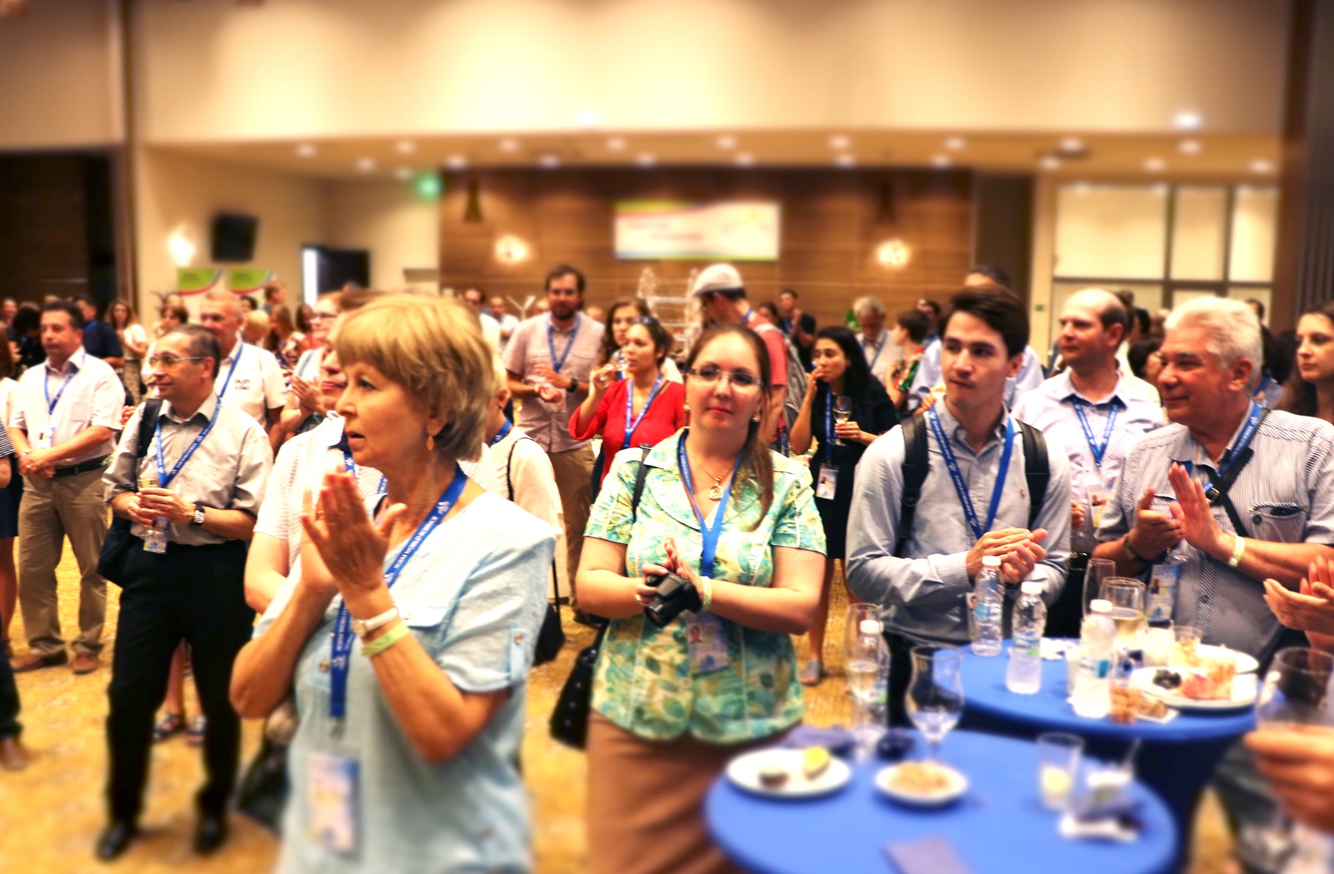 Delegados aplaudiendo en una recepción de conferencia de pie