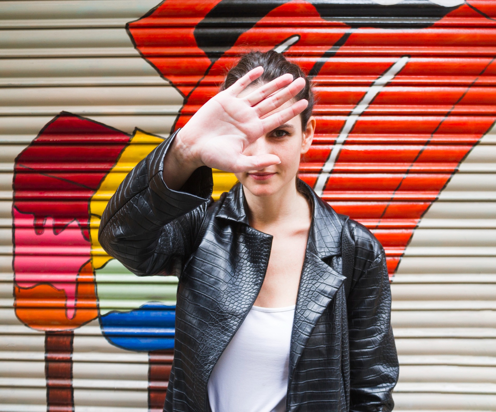 A woman raising her hand in front of a painted street mural