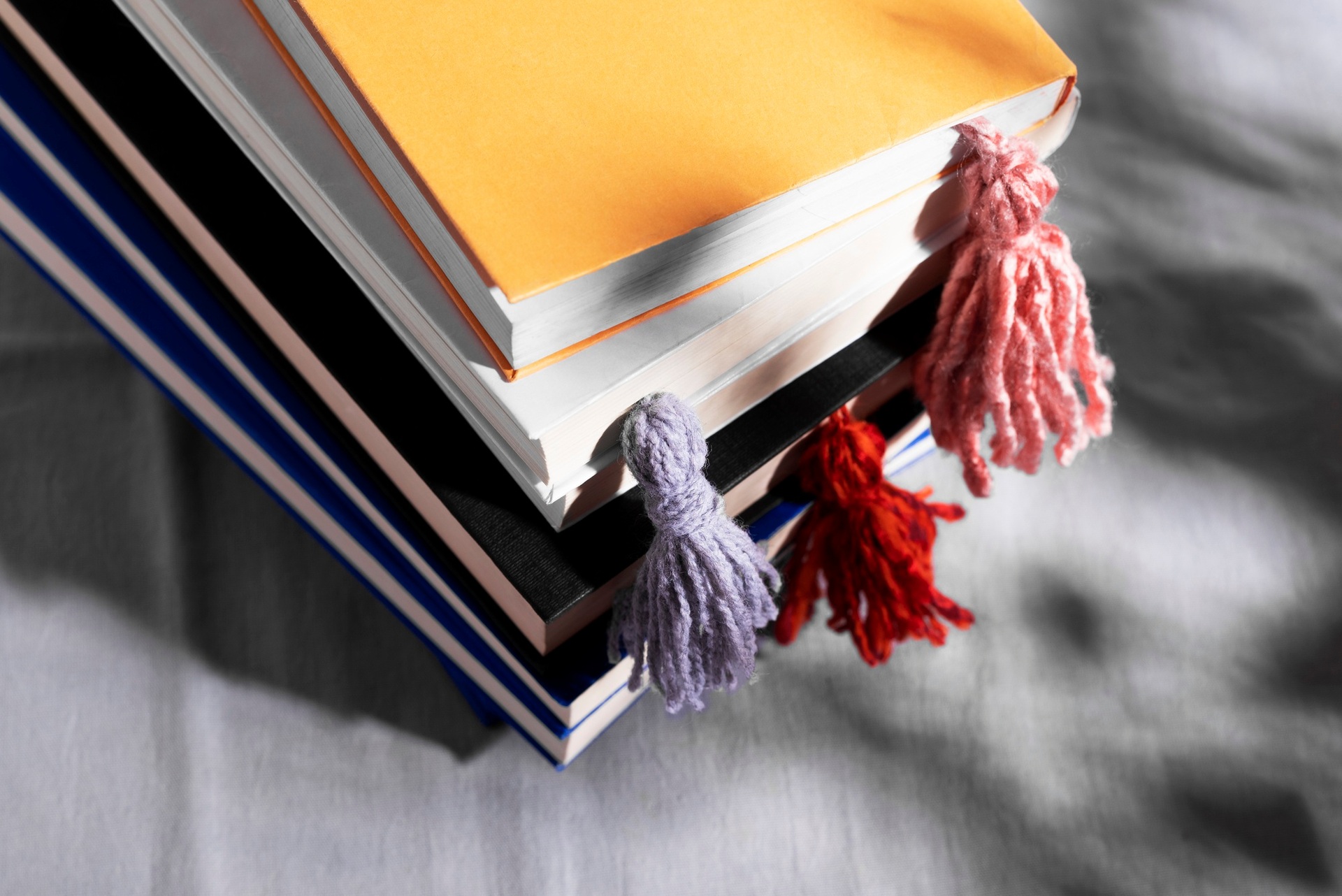 A stack of books with coloured tassel bookmarks