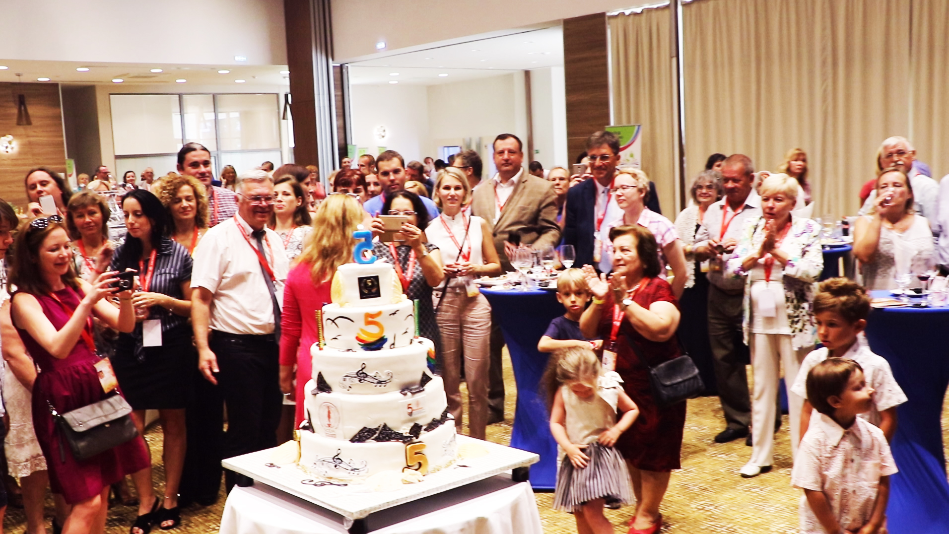 Conference guests applauding beside a celebration cake
