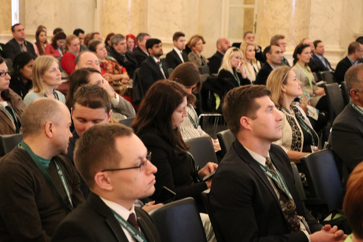 Audience members listening in a chandelier-lit conference hall