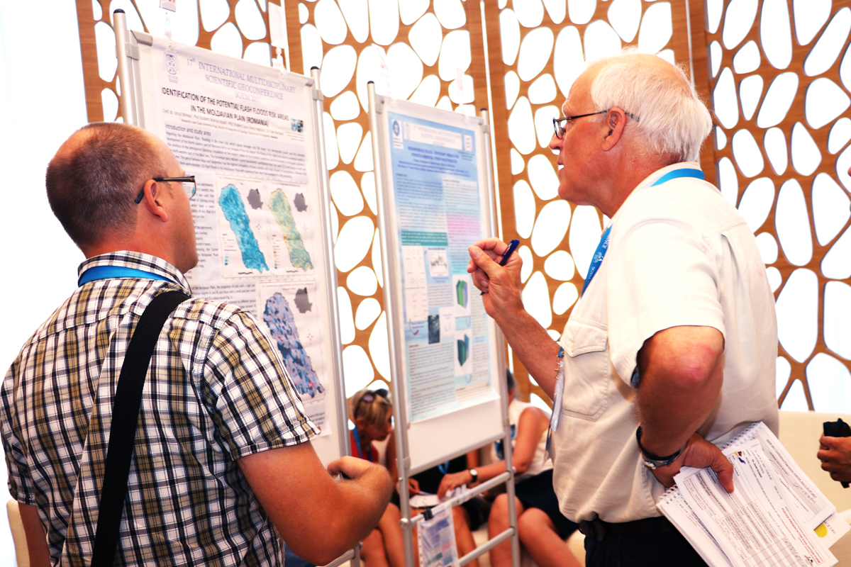Two researchers discussing charts on a scientific poster
