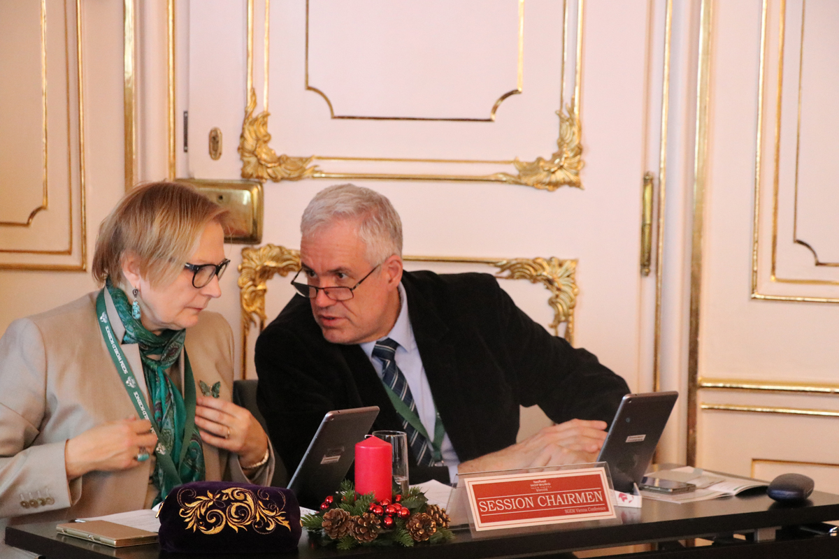 Two session chairs consulting each other at a conference table