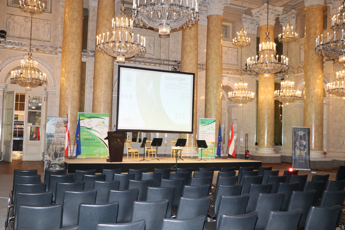 Rows of seats facing an SGEM presentation screen in a gilded hall