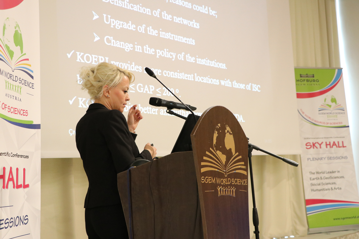 A speaker discussing a projected slide at an SGEM lectern