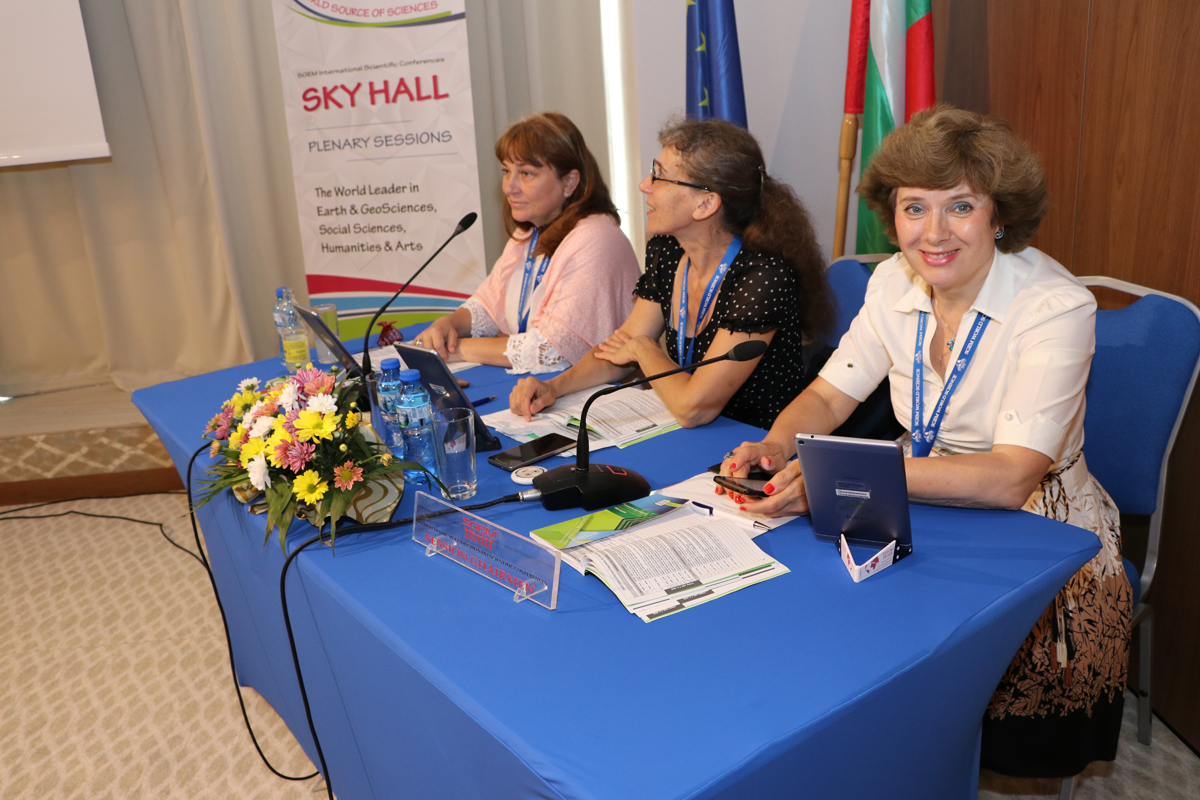 Three session chairs seated behind a blue conference table