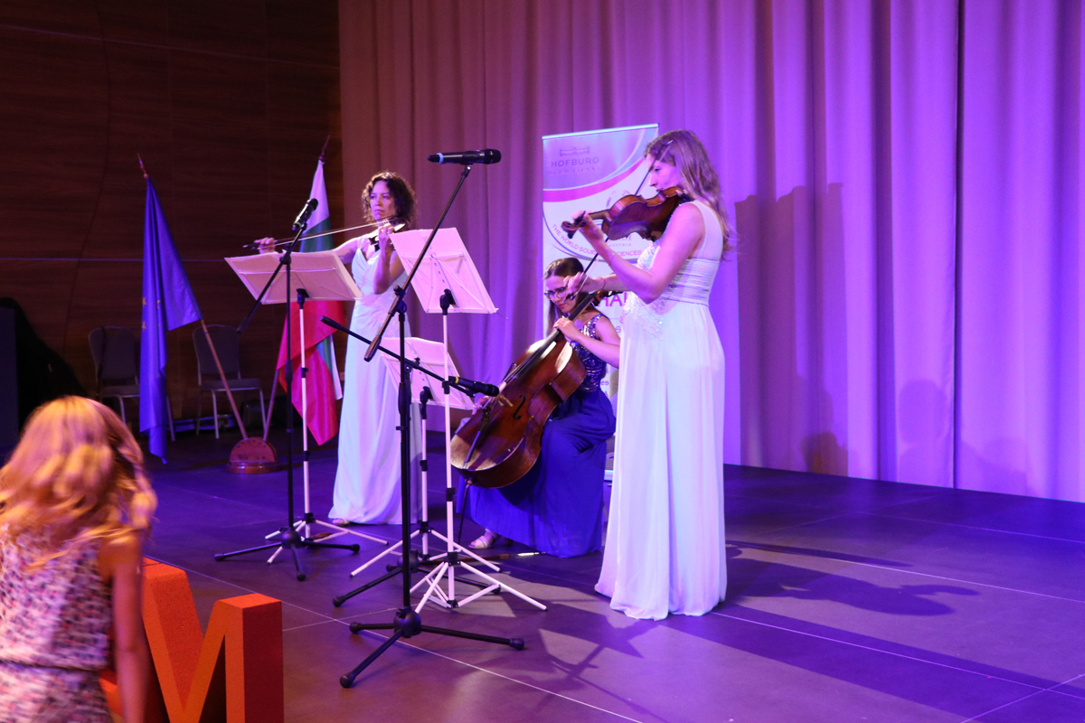 A string ensemble performing on a purple-lit stage