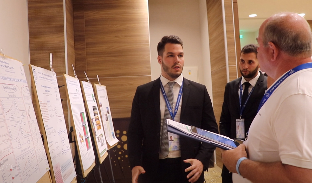 Researchers discussing findings beside scientific poster boards