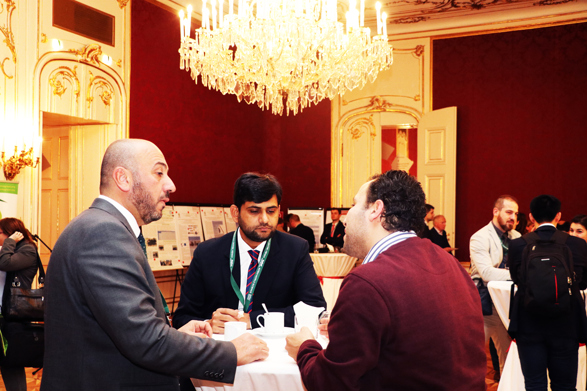 Three delegates discussing research around a reception table