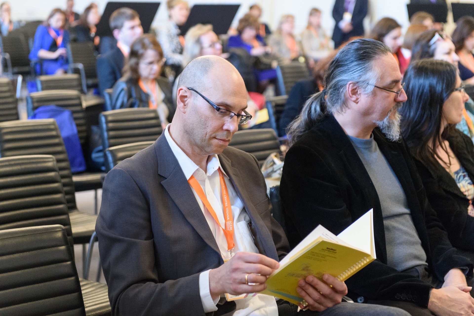 A conference delegate reading a programme in an auditorium