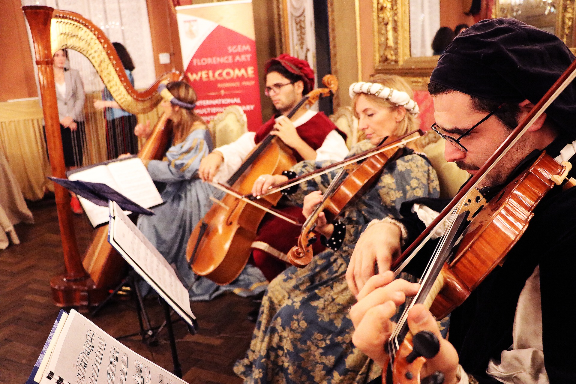 Musicians in historical costumes playing harp, strings and a wind instrument