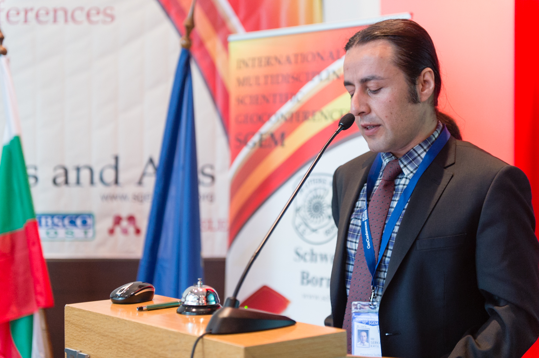 A speaker addressing an SGEM audience from a wooden lectern