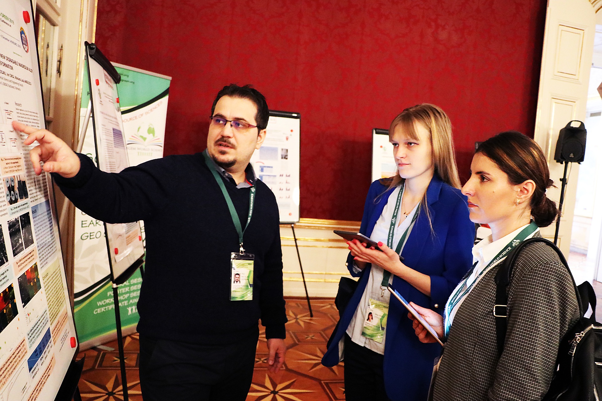 A researcher explaining a scientific poster to two delegates