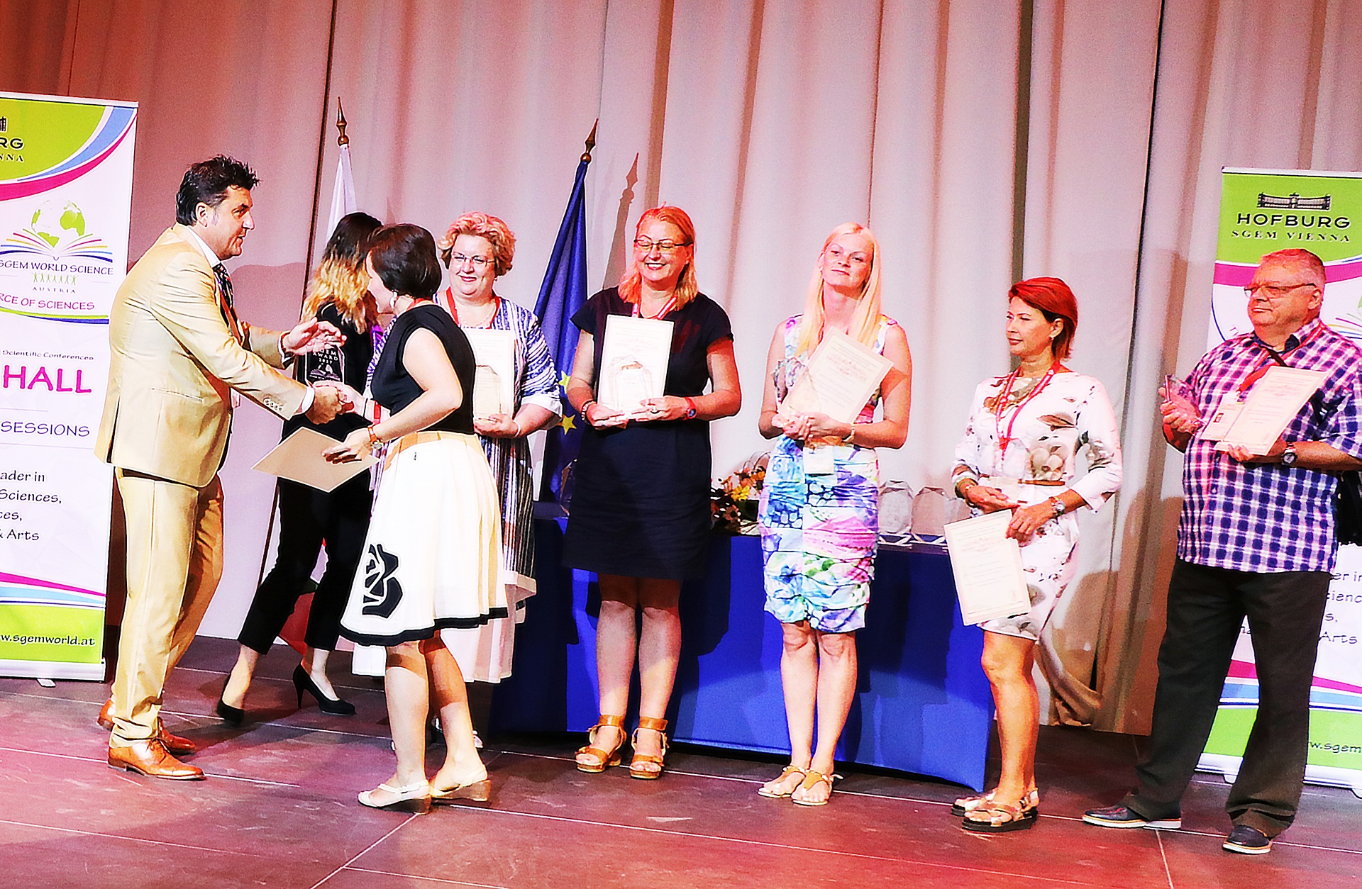 SGEM award recipients lined up on stage during a presentation