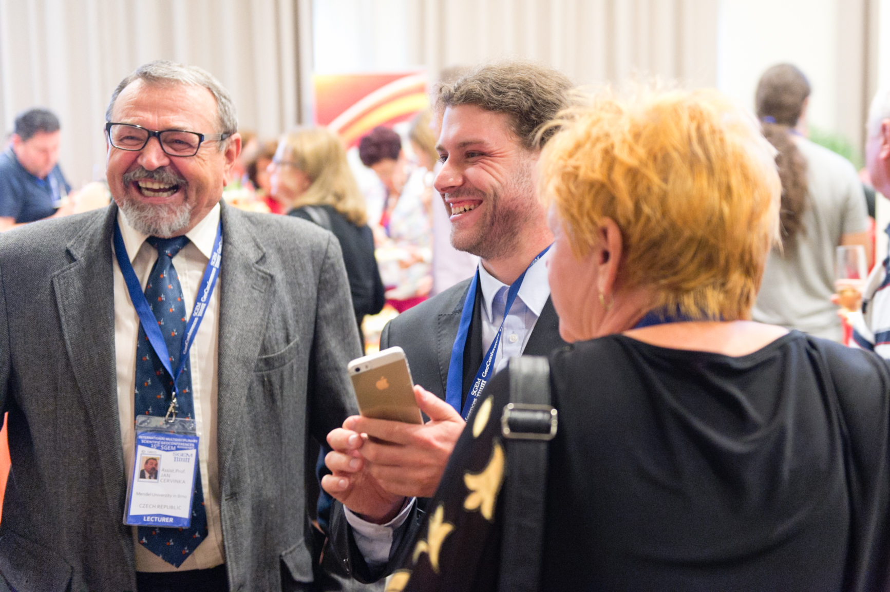Three delegates laughing together during a conference break