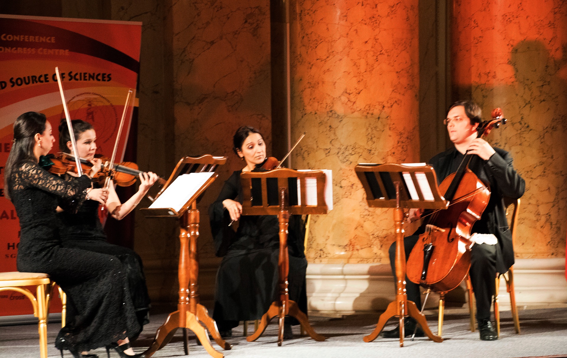 A string ensemble performing between marble columns