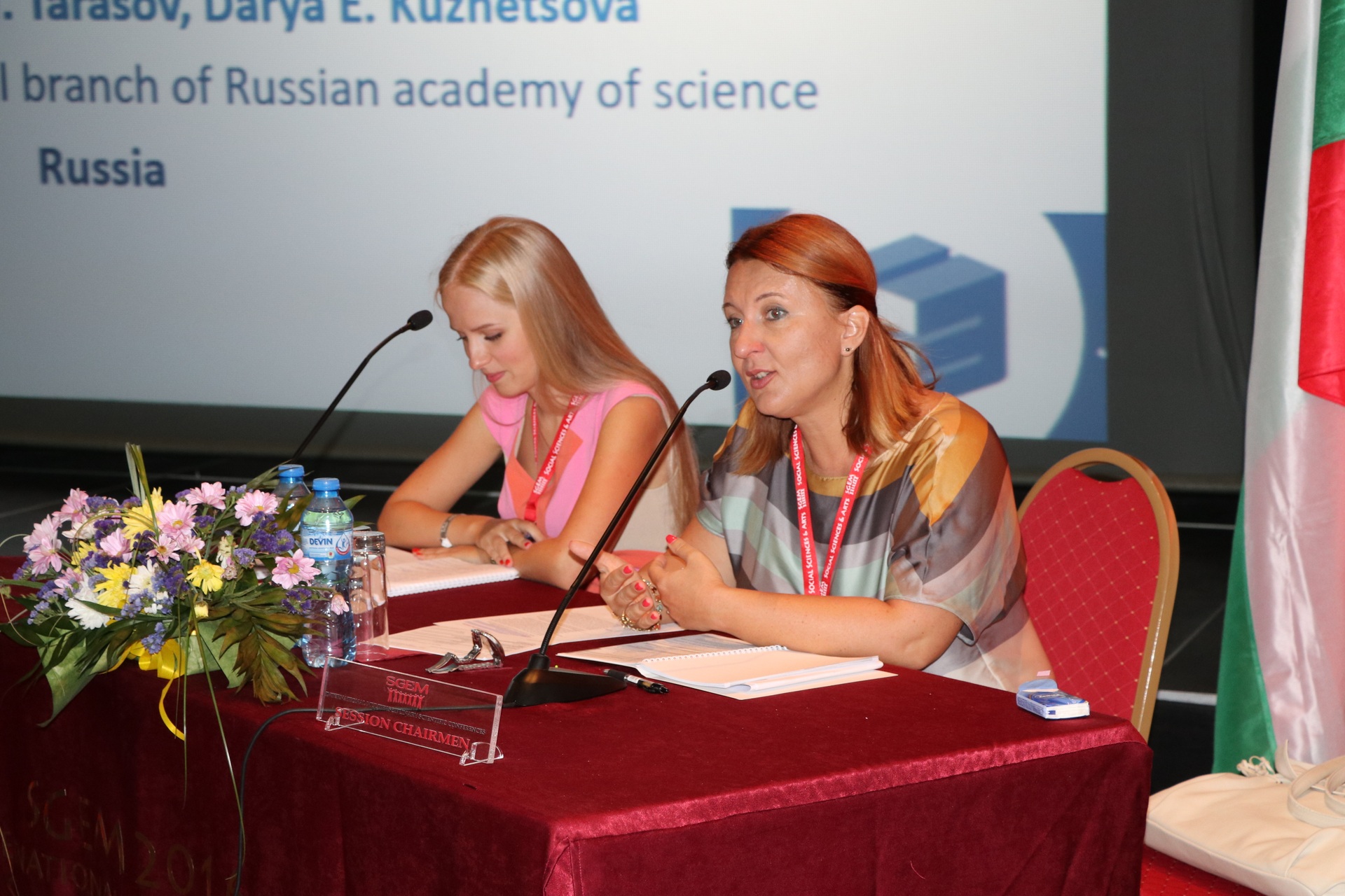 Two researchers speaking at a red conference table