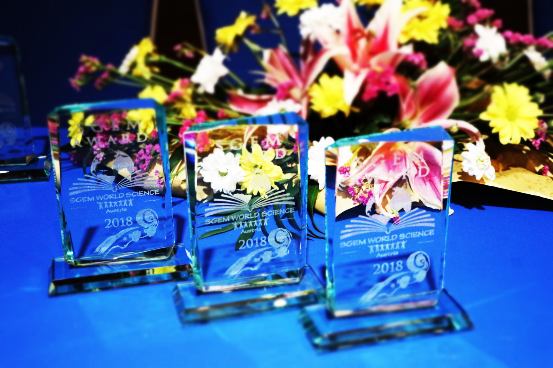 Glass SGEM awards displayed beside a colourful bouquet