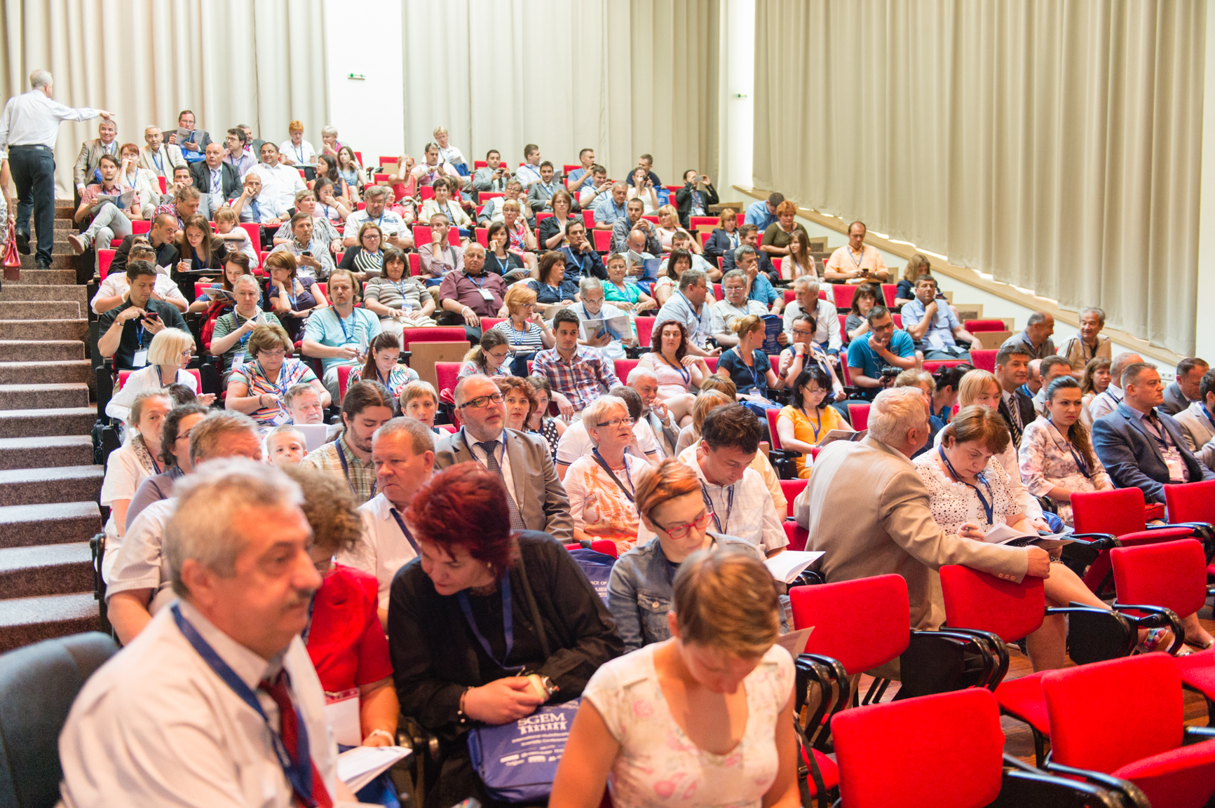 A full scientific conference audience in red auditorium seats