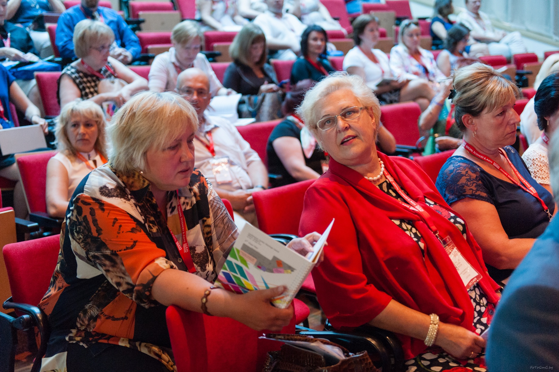 Two delegates talking while holding an SGEM conference programme