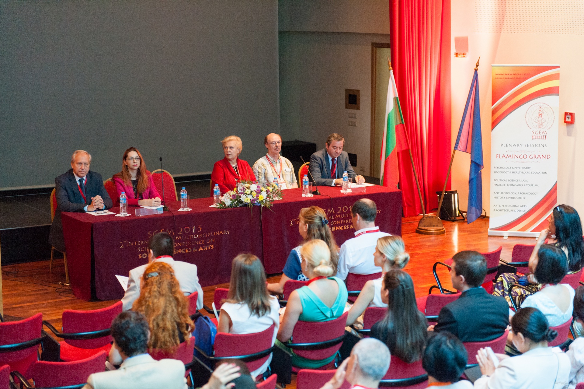A scientific panel seated before an auditorium audience