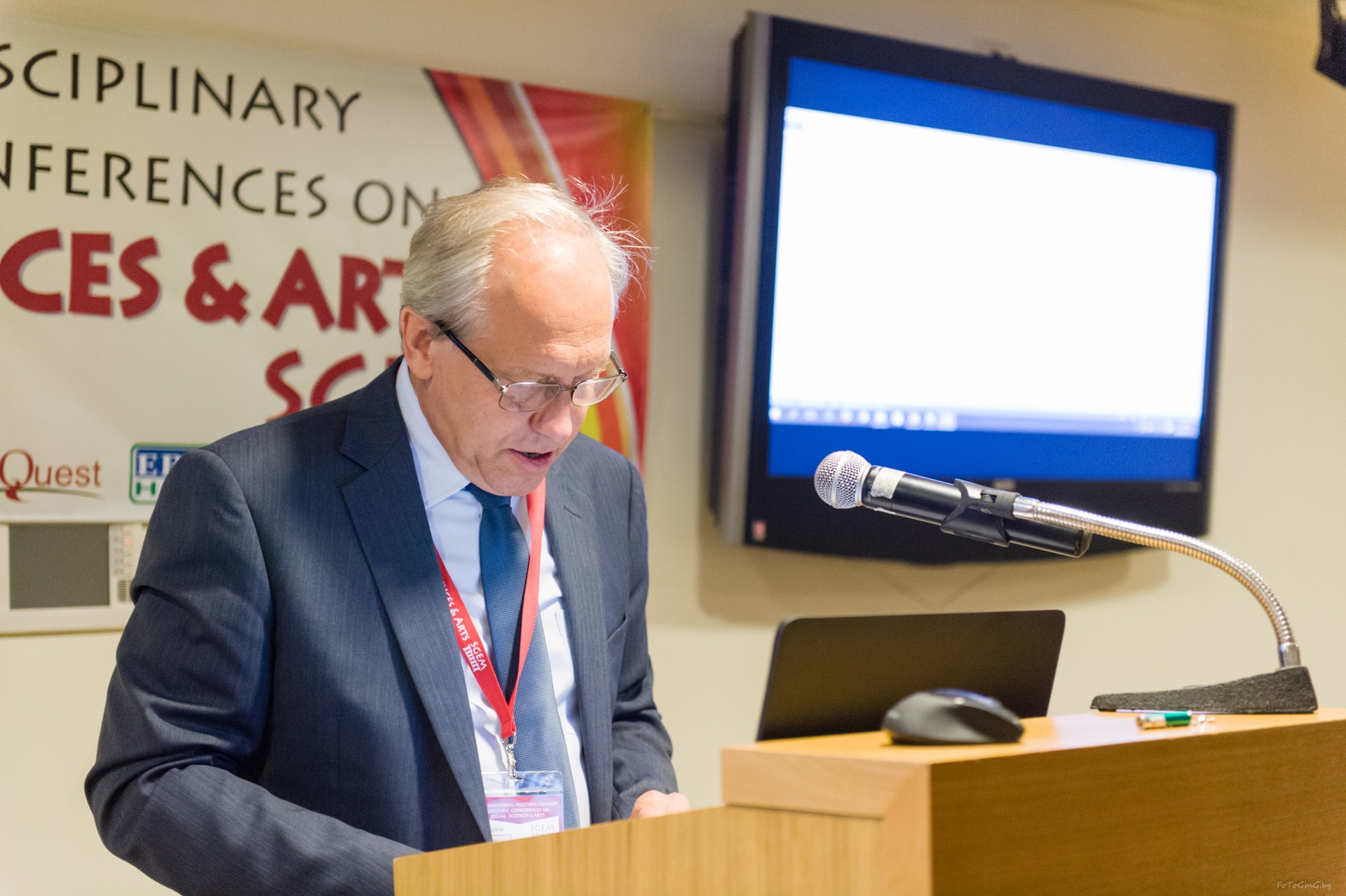 An SGEM speaker reading notes at a wooden lectern