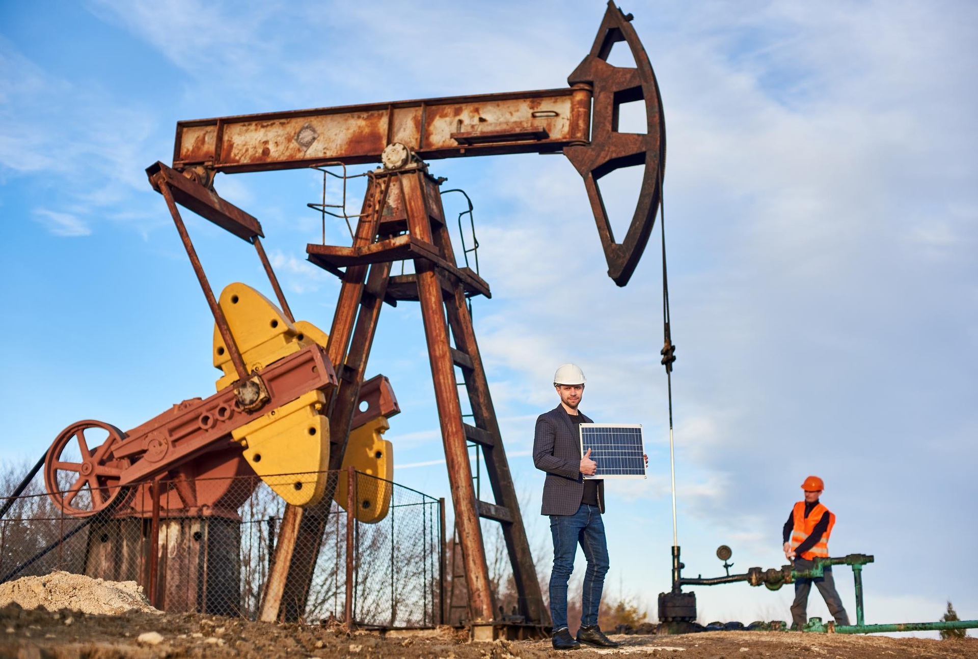 Engineers standing beside an oil pumpjack