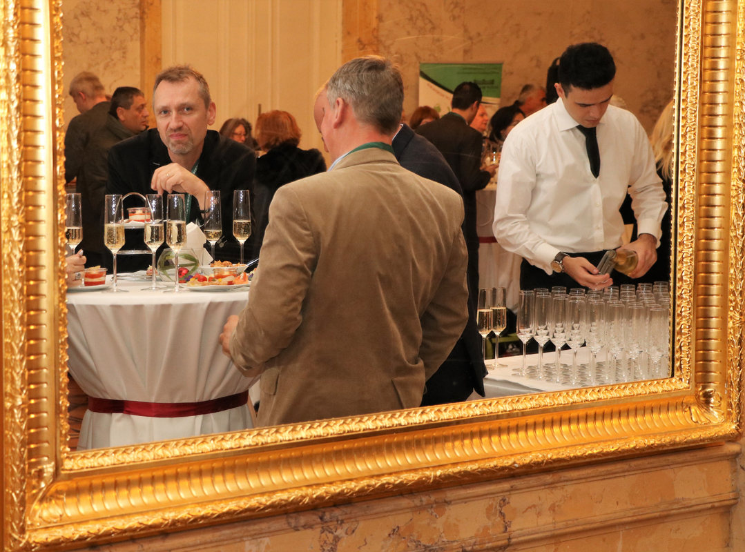 Conference reception reflected in a gilded mirror