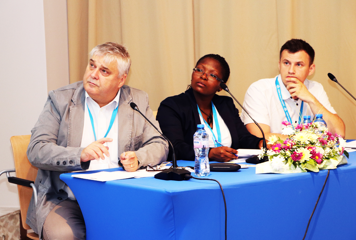 Three session chairs listening at a conference panel table
