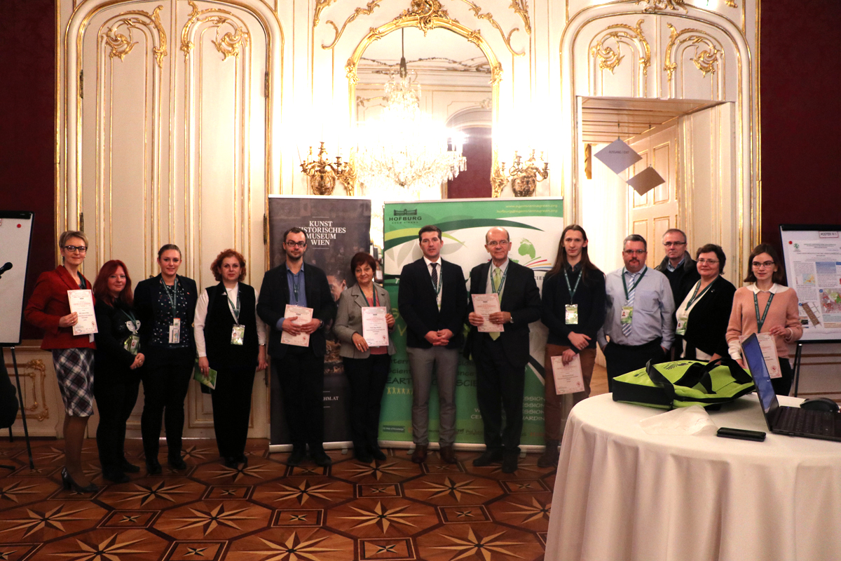 Certificate recipients posing in an ornate conference hall