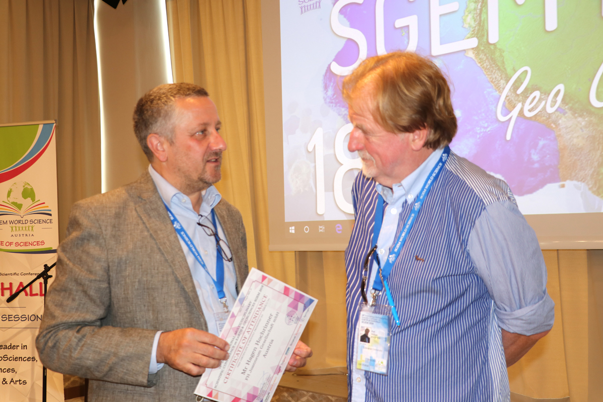 Two SGEM participants talking while holding conference papers