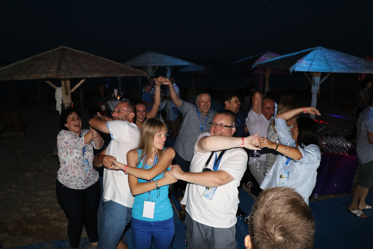 Conference guests dancing together outdoors at night