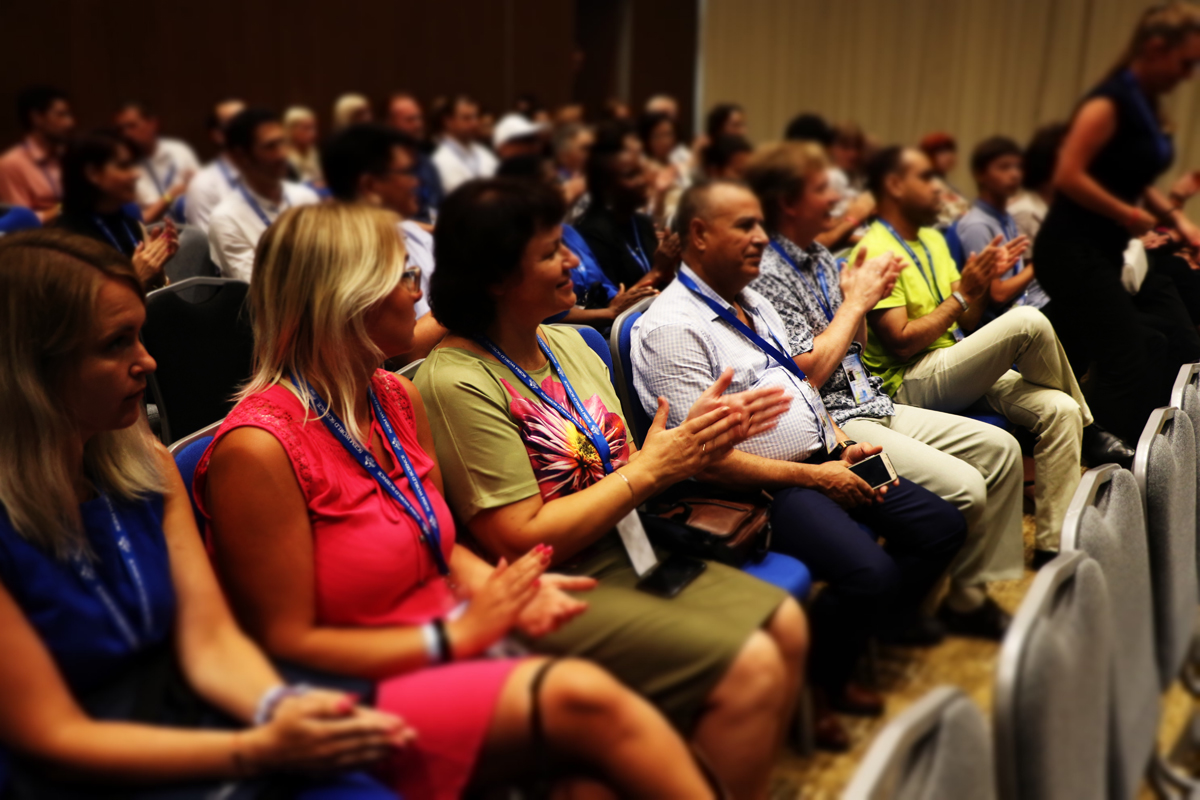 Audience members applauding a conference presentation