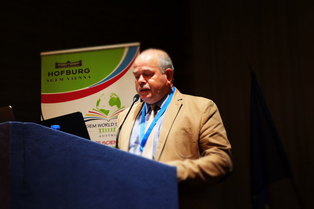 A speaker at a blue lectern during an SGEM plenary session