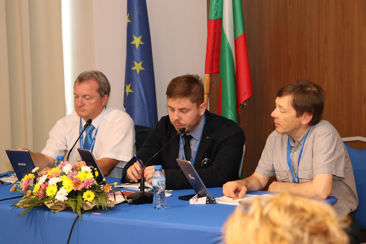 Three SGEM panel members with microphones and conference papers