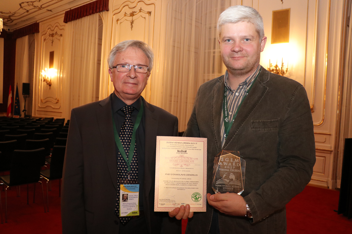 Two delegates posing with an SGEM certificate and glass award