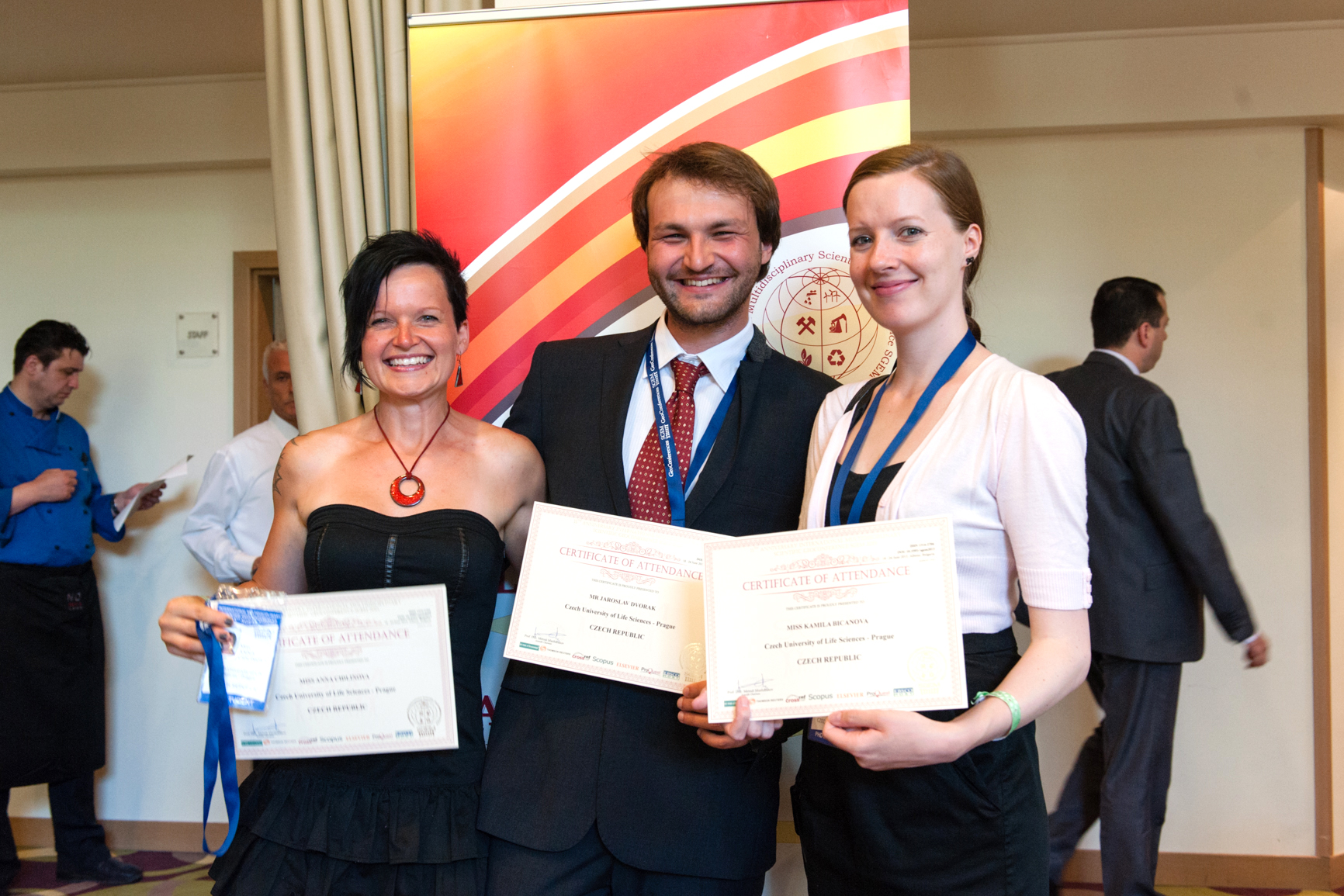 Three conference participants posing with certificates