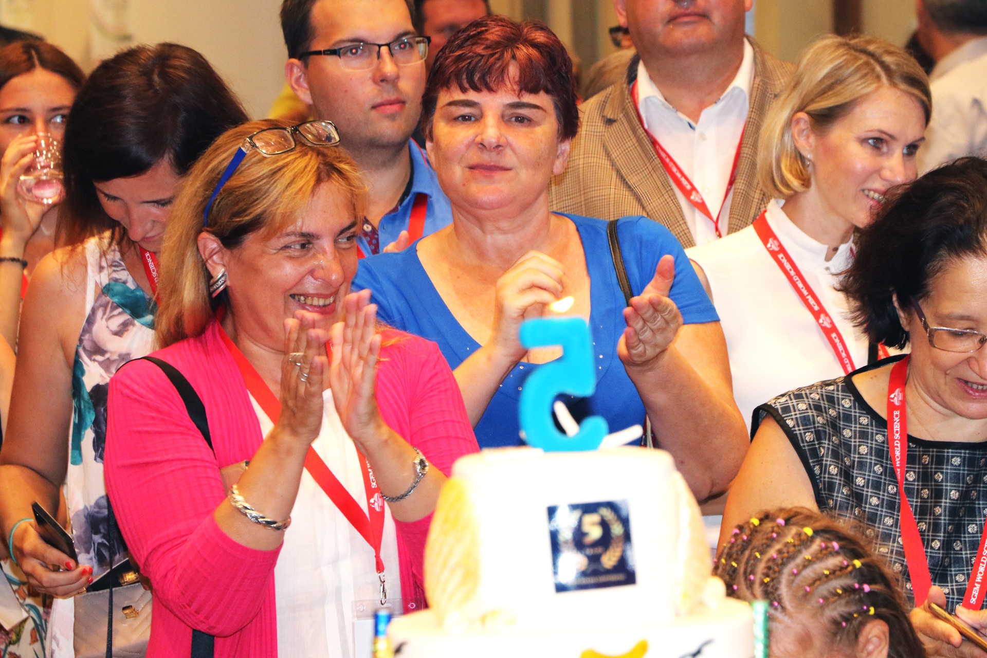 Conference participants applauding beside a celebration cake