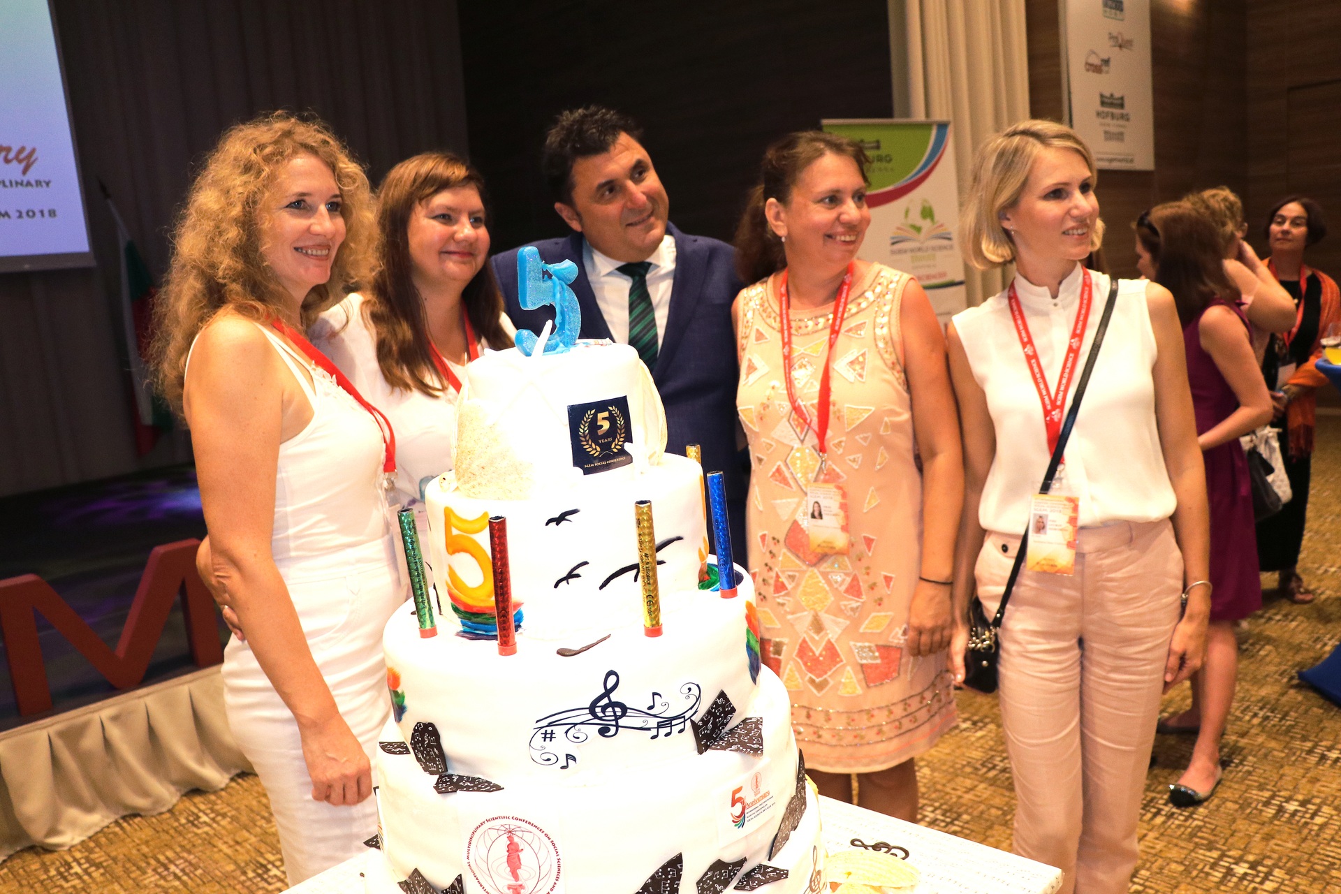 Five participants posing behind a decorated conference cake